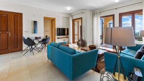Una sala de estar moderna con sofás color turquesa, un comedor y un televisor.