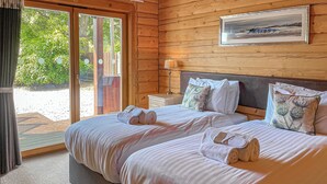 Una cama doble con dos almohadas, una mesita de noche con lámpara, y un cuadro enmarcado en la pared.