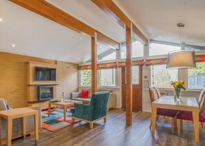 A spacious living area with a TV, seating, a dining table, and a fireplace. - Very comfortable lodge with one double and one twin. (Millom)