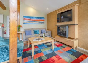 A modern living room with a sofa, coffee table, TV, and fireplace. - Very comfortable lodge with one double and one twin. (Millom)