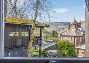 Une vue d’un bâtiment au revêtement extérieur en bois, agrémenté d’une enseigne, et entouré de verdure et d’un paysage montagneux.
