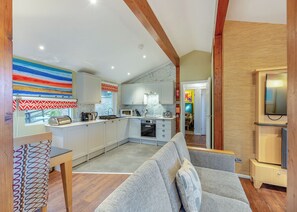A modern kitchen with white cabinets, a grey sofa, and a TV. - Very comfortable lodge with one double and one twin. (Millom)