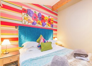 A hotel room with a striped wall, a bed with pillows, a nightstand, and a lamp. - Very comfortable lodge with one double and one twin. (Millom)