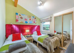 A hotel room with two beds, a large mirror, a window with a view, and a ceiling fan. - Very comfortable lodge with one double and one twin. (Millom)