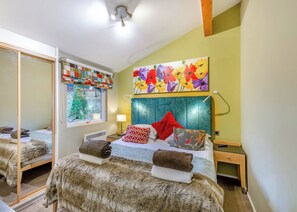Un dormitorio con cama, espejo, ventana con vistas y un cuadro colorido en la pared.
