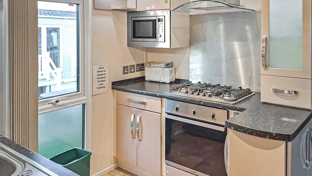 A compact kitchen with a microwave, stove, oven, and a trash bin. - Holiday home with one double with en suite, and one twin. (Tollerton, York)