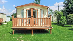 A mobile home with a wooden deck, large windows, and a small porch. - Holiday home with one double with en suite, and one twin. (Tollerton, York)
