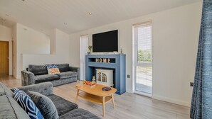Ein modernes Wohnzimmer mit Kamin, Flachbildfernseher und Sofa.