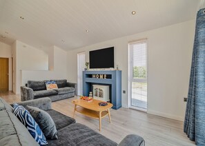 A modern living room with a fireplace, a flat-screen TV, and a sofa.