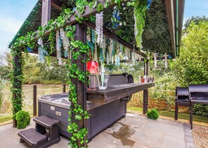 An outdoor hot tub area with a grill, steps, and a pergola with hanging plants. - 1 bedroom accommodation in South Duffield, Nr York (South Duffield, Nr York)