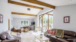 Ein geräumiges Wohnzimmer mit Ledersofas, einem Couchtisch und einem Fernseher.