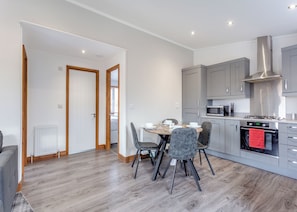 A modern kitchen with grey cabinets, a microwave, and a stove. There is a dining area with a table and chairs.