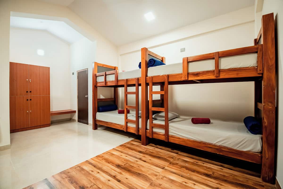 Une chambre avec des lits superposés, une armoire et un petit coin cuisine.