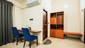 Quarto compacto com escrivaninha, duas cadeiras, guarda-roupa e um banco.