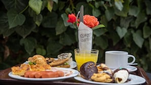 A breakfast tray with croissants, sausages, pastries, and a glass of orange juice. - Galaxy (Kalabaka)