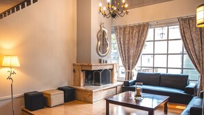 A living room with a fireplace, a sofa, a coffee table, and a lamp. - Galaxy (Kalabaka)