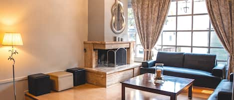 Una sala de estar con chimenea, un sofá, una mesa de centro y una lámpara.