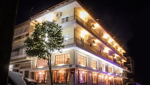 A multi-story hotel with balconies, large windows, and a tree in front. - Galaxy (Kalabaka)