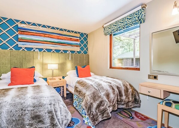 A hotel room with two beds, a large window, a mirror, and a patterned wall. - Traditional lodge with one double and one twin. (Millom)