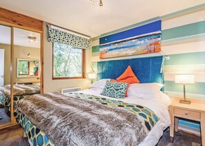 Ein Schlafzimmer mit einem Bett, einem Nachttisch, einem Spiegel und einem Fenster mit Blick.