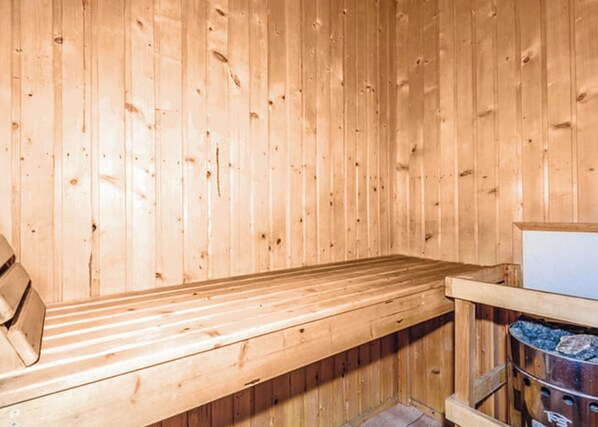 Eine Holzsauna mit einer Bank und einem Steinofen.
