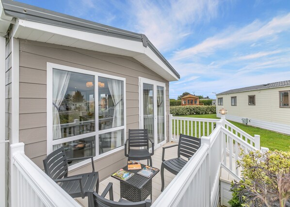 A covered outdoor area with a table and chairs, a glass door, and a view of neighboring houses.
