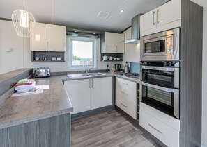 A modern kitchen with a gas stove, built-in oven, microwave, and a large window.