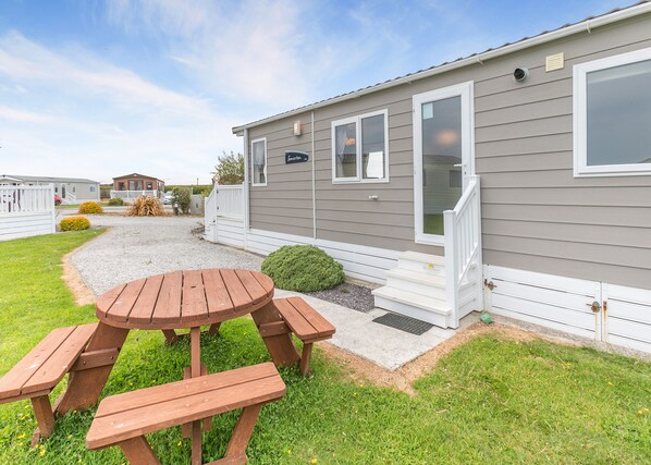 A mobile home with a patio area, a wooden table, and benches.