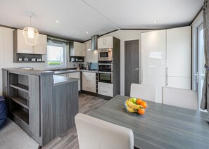 A modern kitchen with a central island, built-in appliances, and a dining area with a fruit bowl.