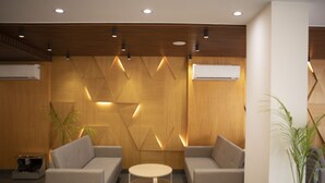 Eine moderne Lobby mit zwei Sofas, einem runden Tisch und einem geometrischen Wanddesign.