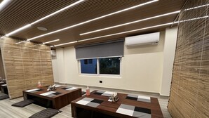 Ein moderner Konferenzraum mit Holztischen, schwarz-weißen Karomotten und grauen gepolsterten Bänken.