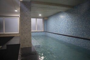 Una piscina interior con agua cristalina, paredes de azulejos y techo de madera.