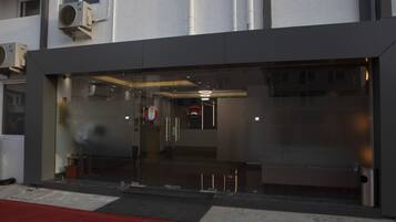 A modern building with a glass entrance, air conditioning units, and a visible fire hydrant.