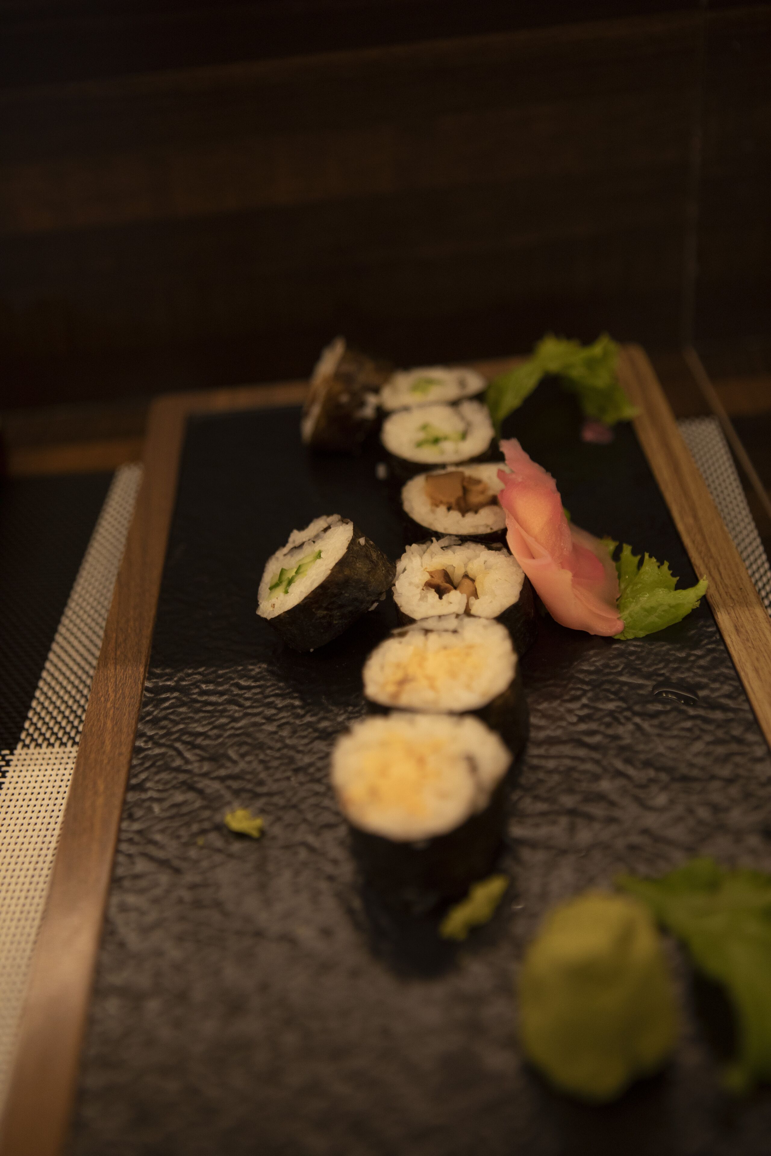 Eine Sushi-Platte mit verschiedenen Sushi-Sorten auf einer schwarzen, strukturierten Oberfläche.