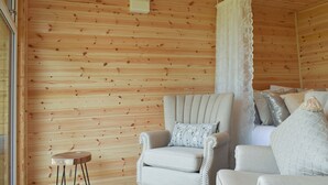 Une pièce aux murs en bois, avec un canapé, un fauteuil et une petite table.