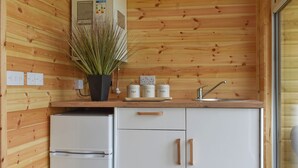 Une cuisine avec des murs en bois, un réfrigérateur blanc, un évier et des placards dotés de poignées.