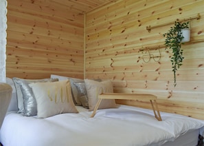 A wooden cabin room with a bed, pillows, a hanging plant, and a shelf with glasses. - Escape to a quirky, cosy pod designed for the perfect romantic retreat. (Bubwith)
