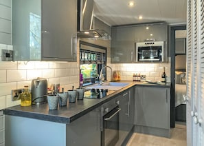 Una cocina moderna con horno empotrado, microondas y lavamanos.