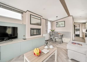 A modern living room with a TV, dining area, and kitchenette.