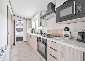 A modern kitchen with a microwave, coffee machine, and oven.