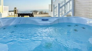 A hot tub with a view of a beach and a house in the background. - Valley View 2 Bed Hot Tub Holiday Caravan Cawsand (St Ann&rsquo;s Chapel, Callington)