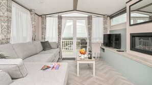 Un salon moderne avec un canapé, une table basse, un téléviseur et un balcon offrant une vue agréable.