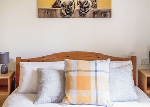Un lit avec une tête de lit en bois, deux oreillers et une œuvre d’art accrochée au mur.