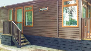 A Kingfisher Lodge building with a wooden exterior, a staircase, and a sign. - Modern two bedroom lodge, one double and one twin with en suite shower. (Langworth)