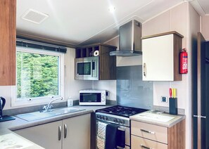 Una cocina compacta con estufa, microondas y pileta.