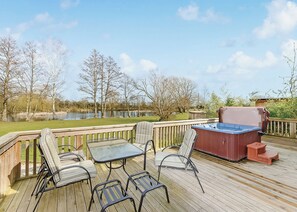 A deck with outdoor furniture, a hot tub, and a view of a lake.