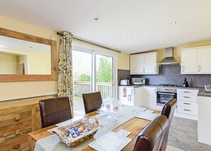 Une cuisine moderne avec des meubles blancs, un four à micro-ondes, une cuisinière et un coin repas avec une table dressée pour deux personnes.