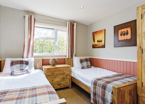 A bedroom with two single beds, a wooden dresser, a window with curtains, and two paintings on the wall. - Luxury lodge with one double and one twin. (Pickering)