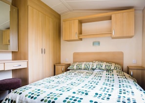 Un dormitorio con cama, cómoda, mesita de noche y espejo.