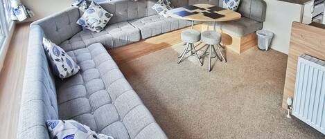 A caravan interior with a sofa set, a round table, and a kitchen area.